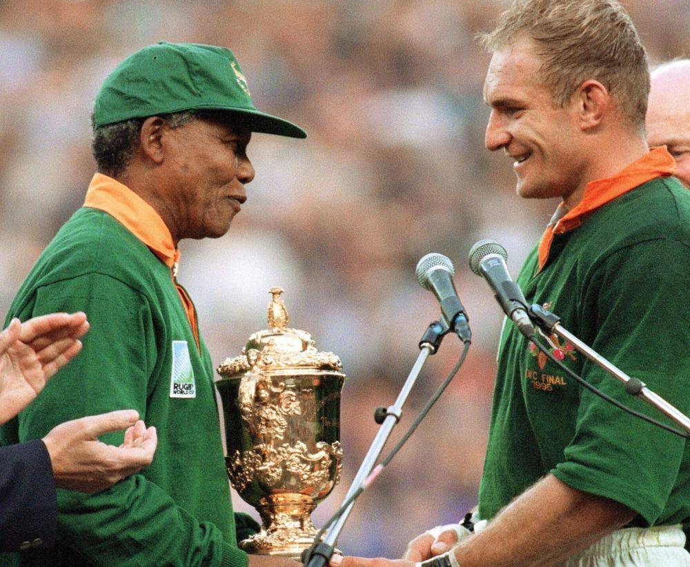 Nelson Mandela menyerahkan trofi Piala Dunia Rugby 1995 pada Francois Pienaar. britannica.com