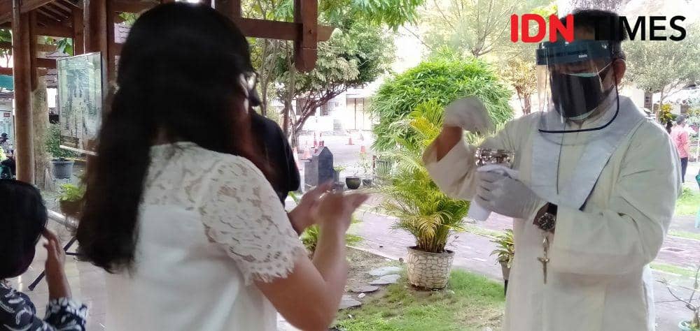 Salah satu umat saat menerima sakramen maha suci diminta menjukurkan tangan agar ada jarak dengan prodiakon. IDN Times/Daruwaskita