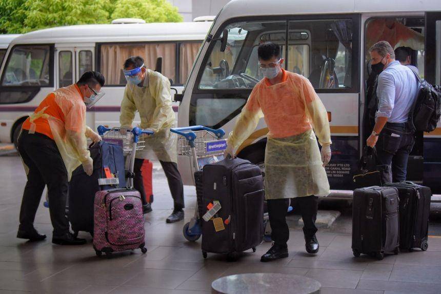 Petugas Bandara Changi, Singapura, membawa koper pendatang dari Inggris. straitstimes.com
