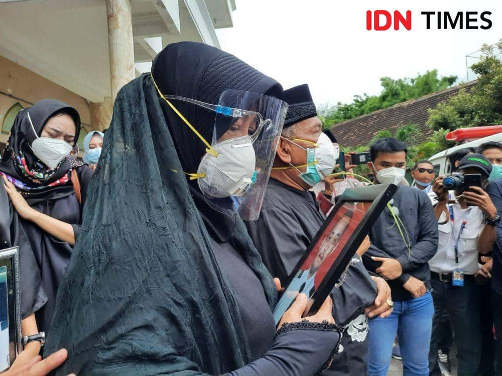 Ninik Andayani megangi foto anaknya sembari memandangi mobil jenazah, Jumat (15/1/2021). IDN Times/Fitria Madia