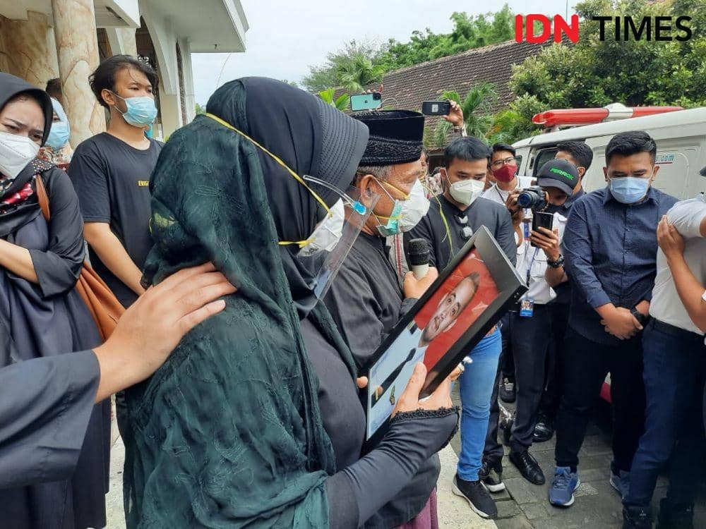 Ninik Andayani megangi foto anaknya sembari memandangi mobil jenazah, Jumat (15/1/2021). IDN Times/Fitria Madia
