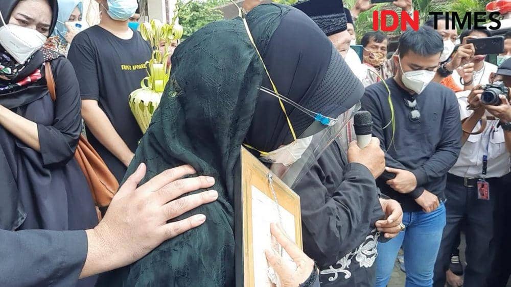 Ninik Andayani megangi foto anaknya sembari memandangi mobil jenazah, Jumat (15/1/2021). IDN Times/Fitria Madia