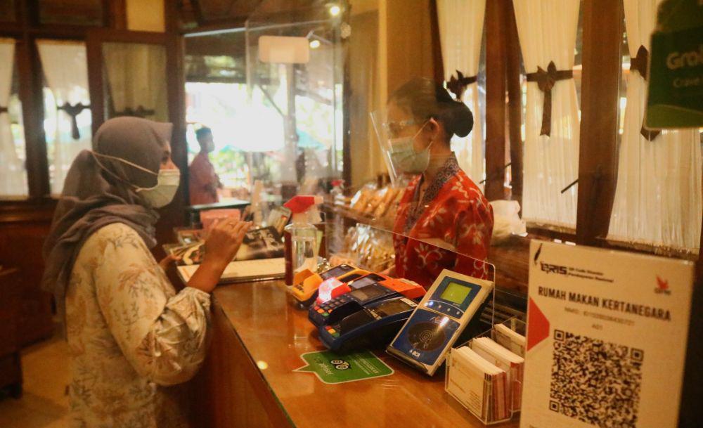 Pelayan melayani pembeli di sebuah kafe di Malang dengan menggunakan protokol kesehatan ketat. IDN Times/Alfi Ramadana