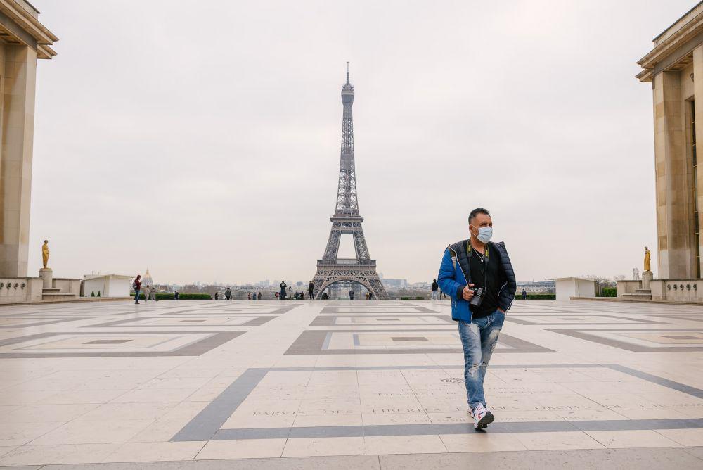 Seorang pria sedang berjalan di area Menara Eiffel Paris sembari memakai masker. (Unsplash.com/Fran Boloni)