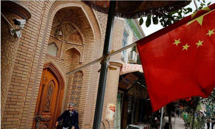 Seorang pria tua terlihat duduk di depan pintu di belakang bendera Tiongkok di Kashgar, Uighur Xinjiang, Tiongkok (6/9/20218). ANTARA/REUTERS/Thomas Peter/aa.