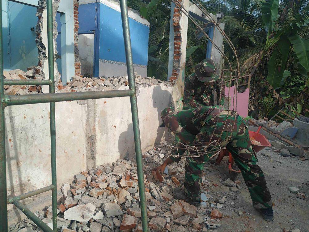 Dua orang anggota TNI sedang membersihkan puing-puing reruntuhan bangunan pasca gempa di Desa Wirotaman, Ampelgading. IDN Times/Alfi Ramadana
