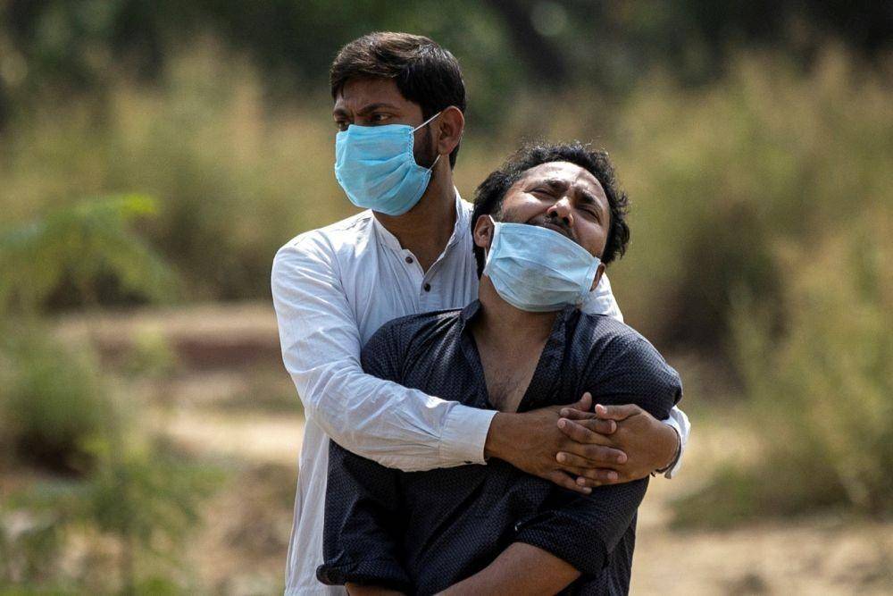 Seorang pria dihibur oleh kerabatnya ketika dia melihat tubuh ayahnya, yang meninggal karena penyakit virus corona (COVID-19), sebelum penguburannya di sebuah kuburan di New Delhi, India, Jumat (16/4/2021). (ANTARA FOTO/REUTERS/Danish Siddiqui)