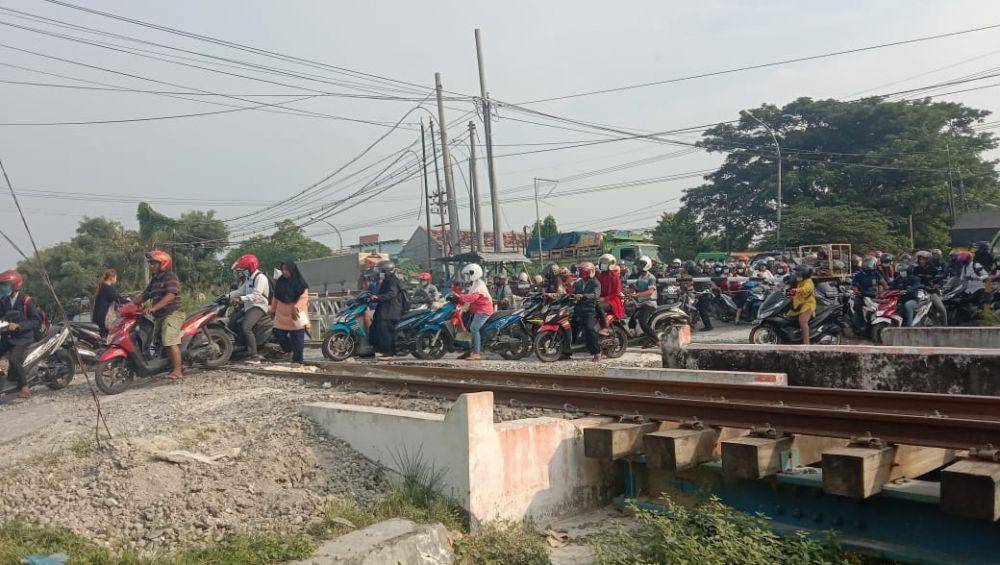Warga kembali melintasi palang pintu KA yang sebelumnya telah dipasangi patok KAI Daop 8 Surabaya. IDN Times/Imron