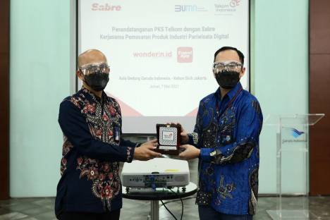Business Telkom M. Fajrin Rasyid (kanan) menyerahkan cendera mata kepada Direktur Teknik Garuda Indonesia Rahmat Hanafi usai penandatanganan kerja sama untuk pemasaran bersama platform digital pariwisata, yaitu Wonderin.id dari Telkom dan TravelAja dari Sabre, anak usaha Garuda, di Jakarta, Jumat (7/5/2021). (Dok. Telkom)