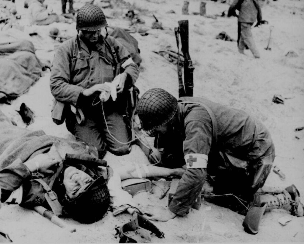 Dua petugas medis yang sedang mengobati tentara yang terluka. (wwiimedic.com)