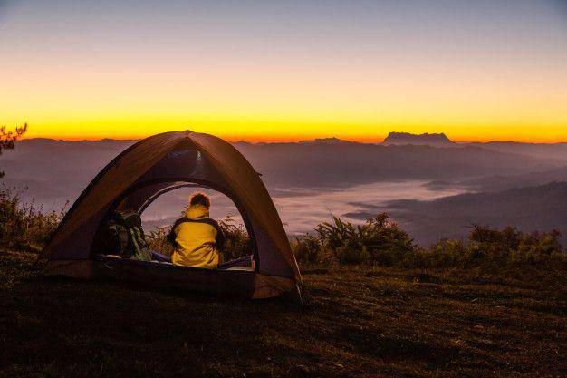 ilustrasi seseorang mendirikan tenda di area pegunungan (freepik.com/jcomp)