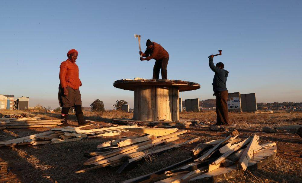 Warga lokal memotong kayu dengan kapak saat penyebaran penyakit virus corona (COVID-19) saat negara tersebut menghadapi pembatasan penguncian lebih disiplin di Soweto, Afrika Selatan, Senin (28/6/2021) (ANTARA FOTO/REUTERS/Siphiwe Sibeko)