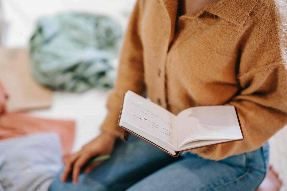 Ilustrasi seorang wanita sedang memegang buku catatan (Pexels.com/Liza Summer)