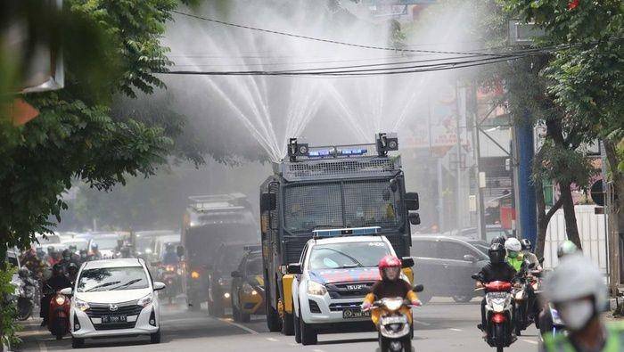 Petugas kepolisian Polresta Kediri menyemprotkan cairan disinfektan menggunakan mobil Armoured Water Cannon (AWC) di jalan protokol Kota Kediri, Jawa Timur, Jumat, 27 Maret 2020. (ANTARA FOTO/Prasetia Fauzani)