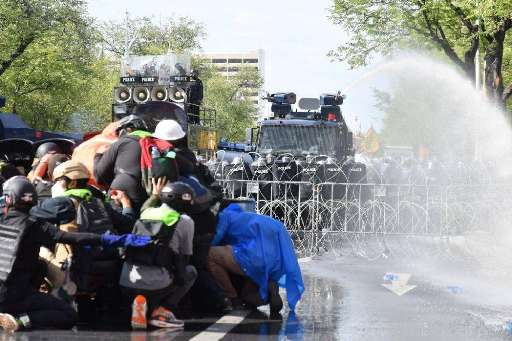 Demonstran Thailand berlindung dari serangan meriam air petugas polisi anti huru-hara. (Twitter.com/Khaosod English)