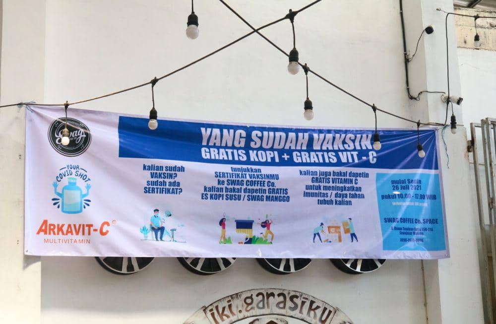 Spanduk pemberitahuan gratis kopi dan vitamin C bagi yang sudah vaksin. IDN Times/Alfi Ramadana
