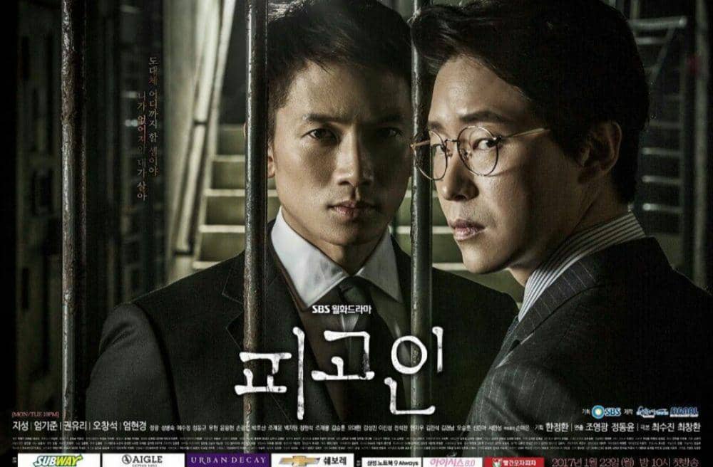 Poster drama Korea Defendant menampilkan dua pria berpakaian jas berdiri di balik jeruji besi dengan ekspresi serius dan tegang.