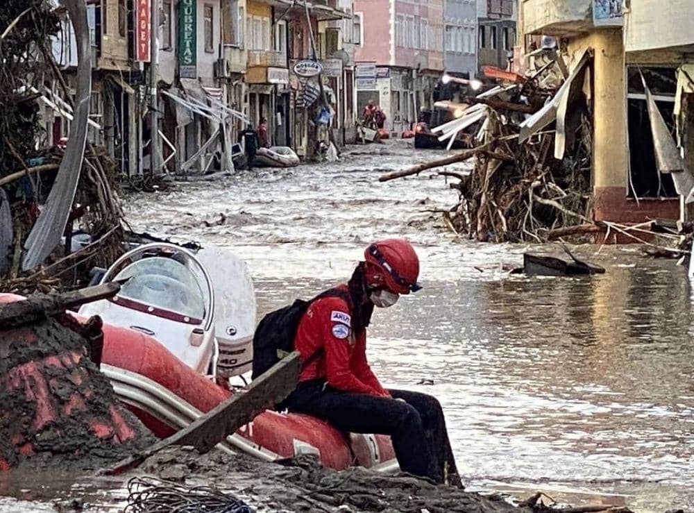 Personel tim tanggap darurat bencana Turki (AFAD) sedang duduk istirahat di tengah puing-puing bangunan yang dihancurkan banjir di Bozkurt, Kastamonu. (Twitter.com/Orta Asya)