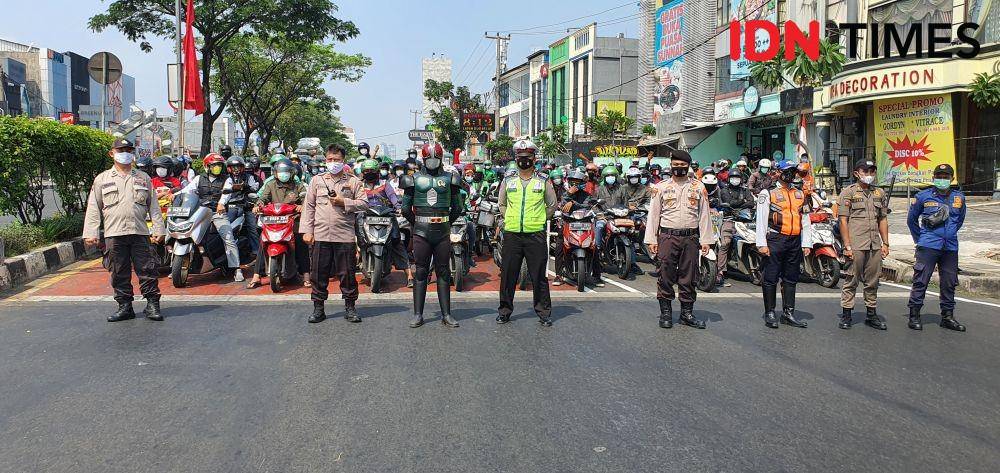 Anggota Polres Metro Depok menghentikan kendaraan pada peringatan kemerdekaan Republik Indonesia di Jalan Raya Margonda, Kota Depok. (IDNTimes/Dicky)