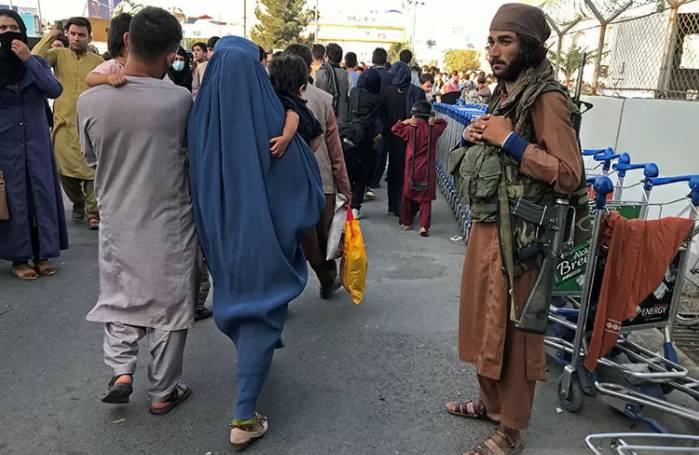 Seorang anggota Taliban berjaga saat orang-orang berjalan di pintu masuk Bandara Internasional Hamid Karzai di Kabul, Afghanistan, (16/8/2021). (ANTARA/REUTERS/Stringer/pri)