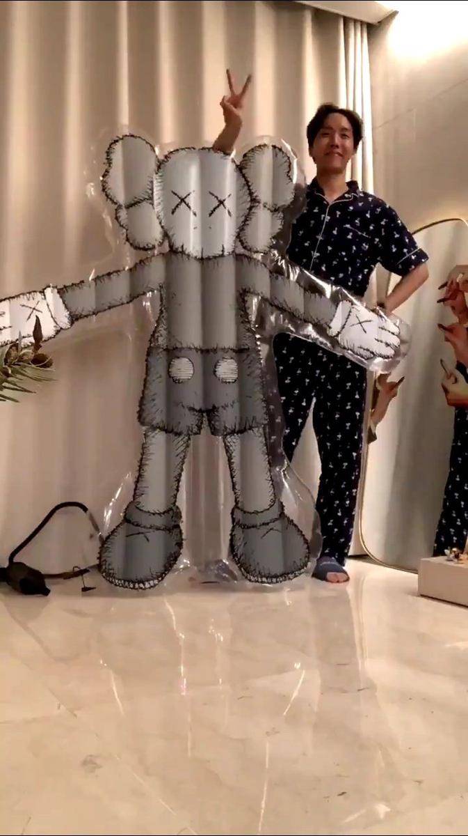tangkapan layar j-hope berpose dengan balon KAWS (twitter.com/bts_twt)