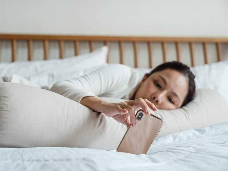 Seorang perempuan bermalas-malasan di kasur.