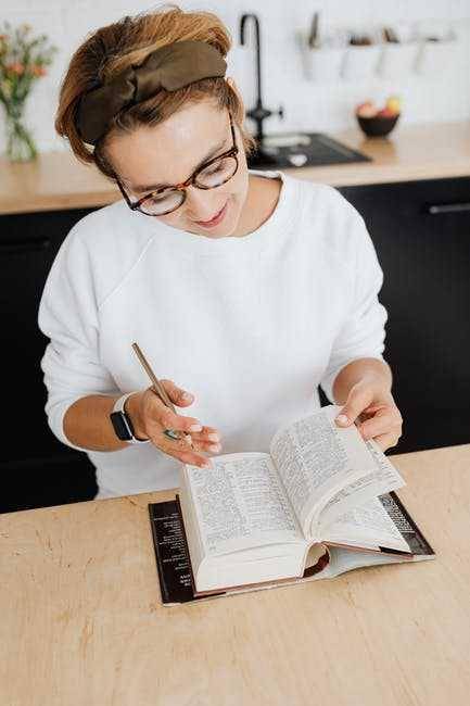 Seorang wanita membaca kamus (pexels.com/KarolinaGrabowska)