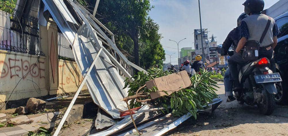 Pohon tumbang menimpa atap seng di pinggir Jalan Raya Kartini, Depok, dengan kabel listrik PLN masih berarus di sekitar lokasi.
