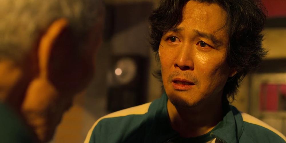 Gi Hun menangis setelah Il Nam memberikan sisa kelerengnya. (dok. Netflix/Squid Game)
