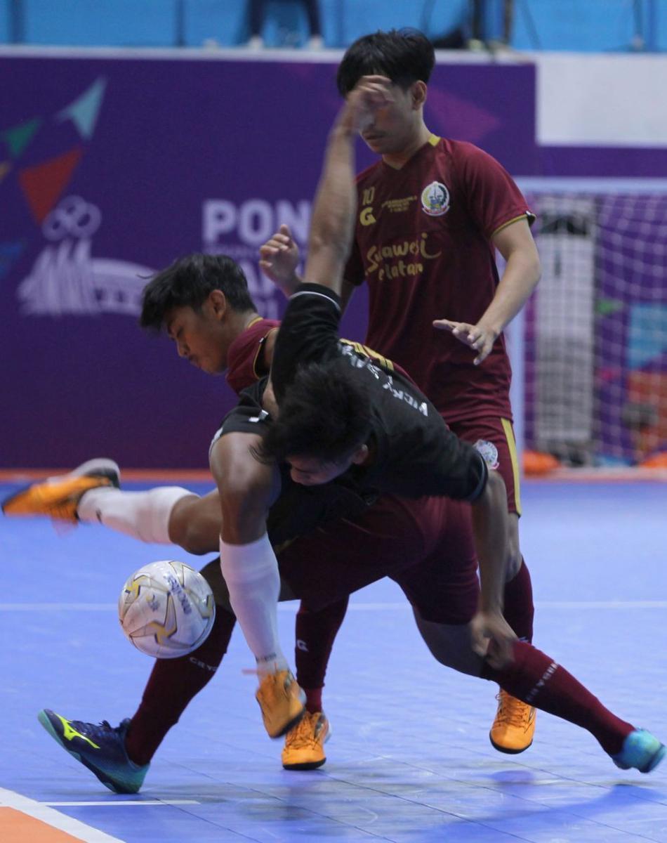 Pemain Jawa timur, Achmad Vicky Irawan (depan) dihalau pemain Sulawesi Selatan, Hasriady dalam pertandingan futsal PON XX Papua di GOR Futsal SP/2 Timika, Sabtu (25/9/2021). PB PON XX PAPUA/ Maleachi Marinsib Palinggi