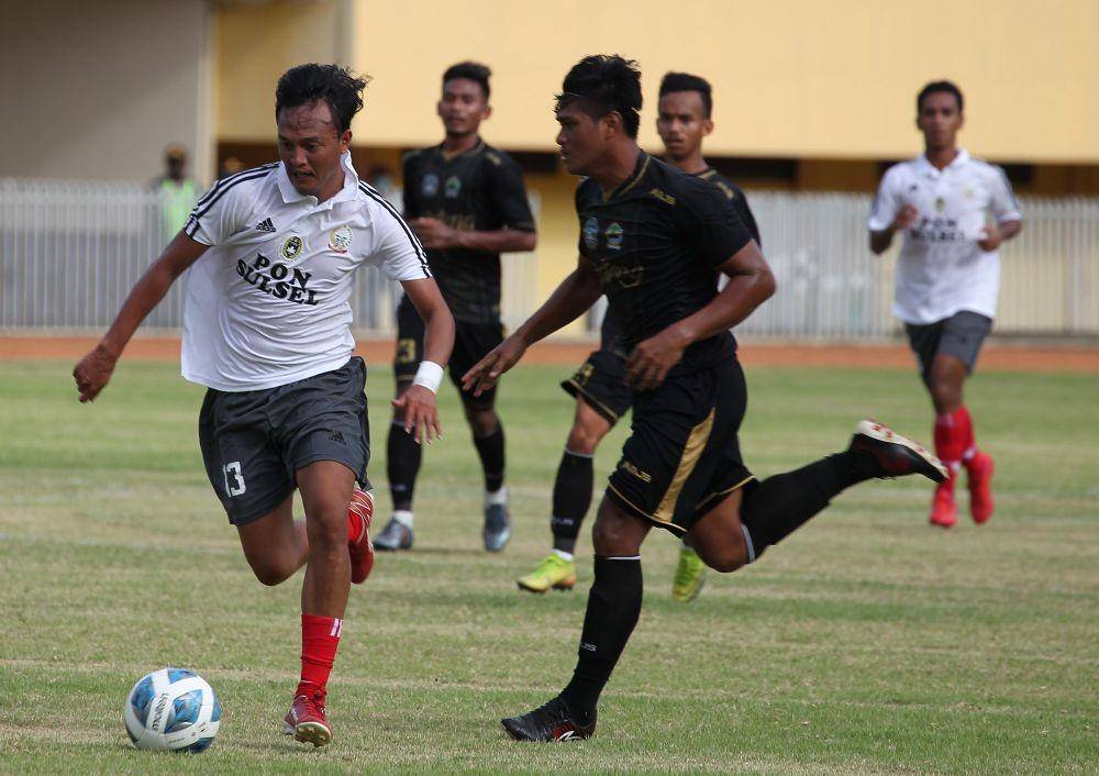Pemain tim sepak bola Sulawesi Selatan, Muhammad Yusril (kiri), saat melewati adangan pemian Jawa Timur Efdal Prasetyo (kanan) dalam laga terakhir babak penyisihan Grup B di Stadion Mandala, Kota Jayapura, Senin 4 Oktober 2021. (PB PON XX PAPUA / Ardy Alvez)