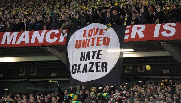 Para suporter Manchester United membentangkan spanduk protes terhadap pemilik klub. (edition.cnn.com)