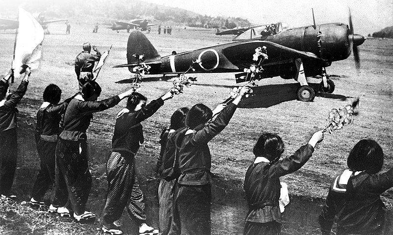 Para siswi menyemangati pilot Kamikaze dengan mengibarkan bunga sakura sebelum pilot lepas landas untuk terakhir kalinya (Wikipedia Image)