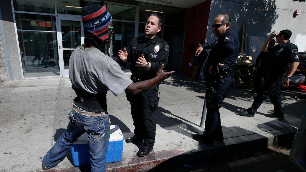 Petugas polisi Los Angeles berbicara dengan seorang pria tunawisma di San Pedro Street di sepanjang jalur ski di pusat kota L.A. (Mark Boster / Los Angeles Times)