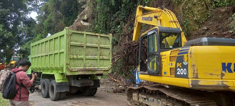 Petugas membersihkan material longsor di Jalan lintas Medan - Berastagi, tikungan PDAM Tirtanadi, Deliserdang, Rabu (27/10/2021). (Istimewa)