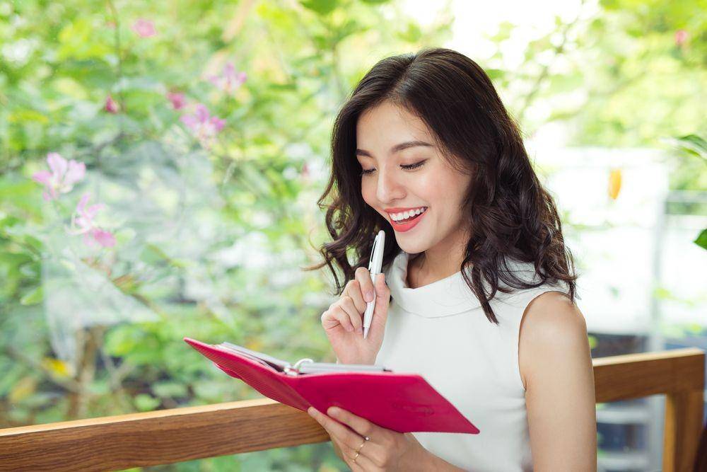Seorang cewek yang sedang menulis di buku catatannya (Shutterstock/Makistock)