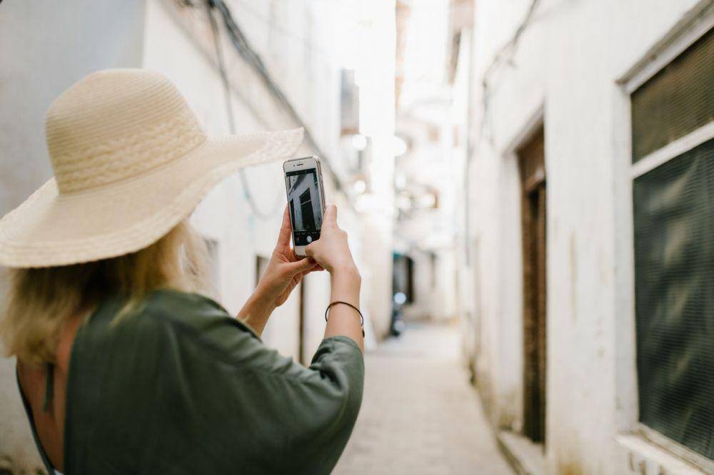 Seorang wanita mengambil foto dengan smartphone. (pexels.com/JuliaVolk)