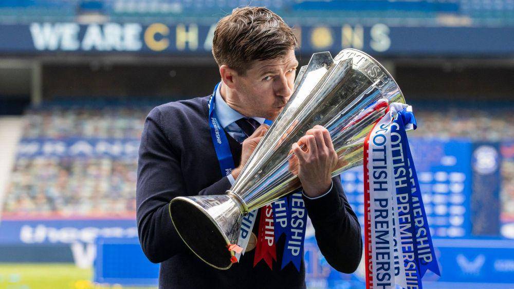 Steven Gerrard mencium trofi Scottish Premiership. (skysports.com)