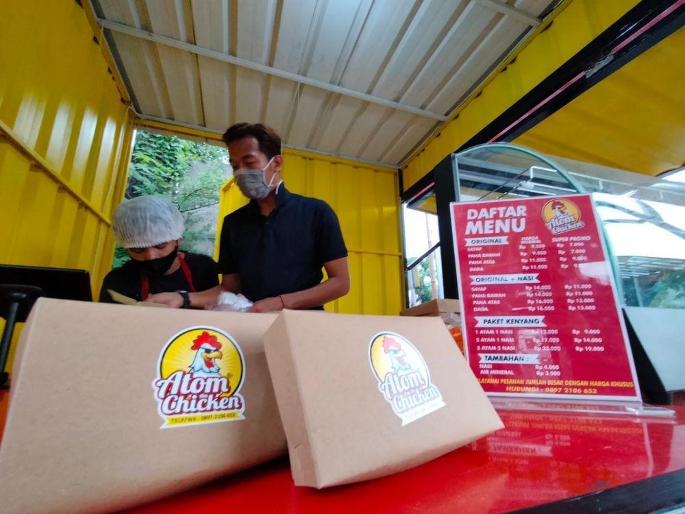Fery Rizkiawan, saat melayani pembeli di gerai ayam goreng miliknya. Dok. Istimewa.