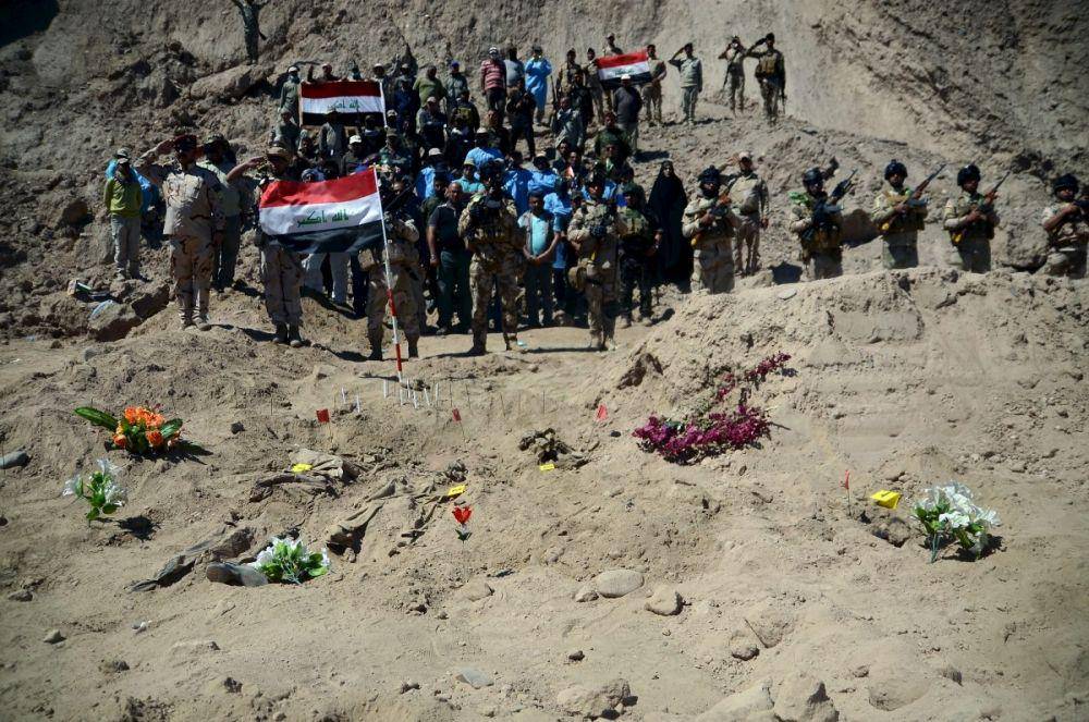 Tentara raqi memberi hormat saat berdiri di samping kuburan massal tentara Syiah dari Kamp Speicher yang telah dibunuh oleh militan ISIS di kompleks mantan presiden Irak Saddam Hussein di Tikrit. (ibtimes.co.in/Reuters)