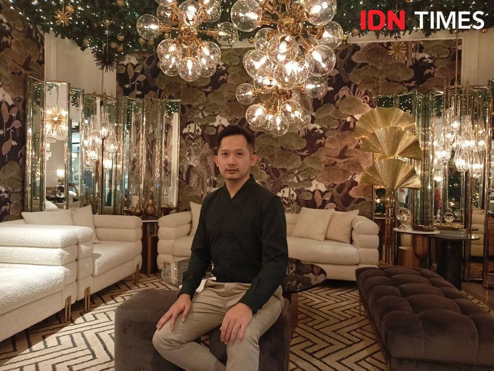 Ronald Humardani, Principal of Roum Design bersama karya miliknya, yakni instalasi "Lights of Hope" yang dibuat melalui kerja sama dengan Eichholtz. 24 November 2021. (IDN Times/M. Tarmizi Murdianto)