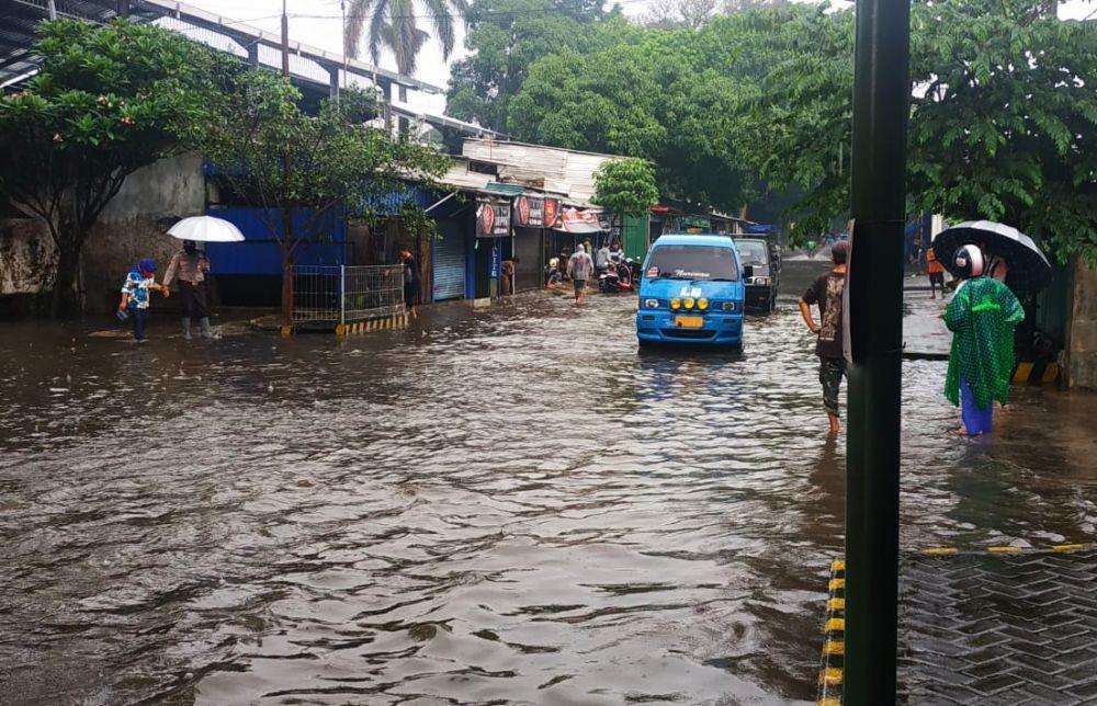 Sebuah mobil angkutan kota memaksa melintas jalan yang tergenang air di Kota Malang. IDN Times/Alfi Ramadana