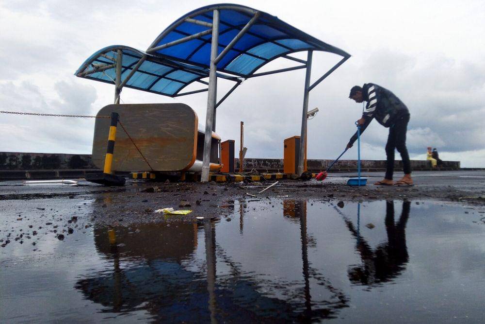 Warga membersihkan puing loket parkiran yang berada di tepi Pantai Teluk Manado, Sulawesi Utara, Rabu (8/12/2021). (ANTARA FOTO/Awit B. Pramono)