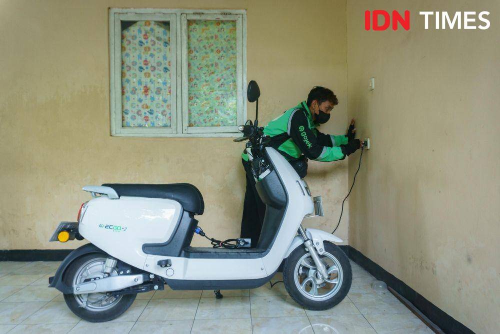 Anis Ramadhani (27), driver ojek online mencabut steker dari stopkontak setelah mengisi baterai motor listrik di rumahnya daerah Kalasan, Sleman, Daerah Istimewa Yogyakarta. (IDN Times/Dhana Kencana)