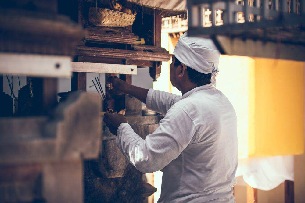 Seorang pria menaruh banten. (pexels.com/belart84)