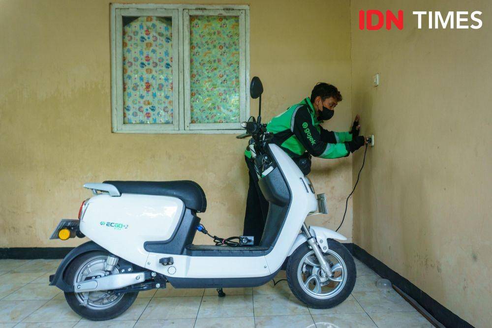 Anis Ramadhani (27), driver ojek online mencabut steker dari stopkontak setelah mengisi baterai motor listrik di rumahnya daerah Kalasan, Sleman, Daerah Istimewa Yogyakarta. (IDN Times/Dhana Kencana)