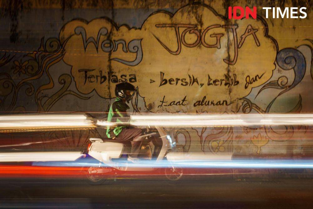 Anis Ramadhani (27), driver ojek online mengantarkan pesanan makanan oleh-oleh ke kawasan Malioboro, Daerah Istimewa Yogyakarta menggunakan motor listrik. (IDN Times/Dhana Kencana)