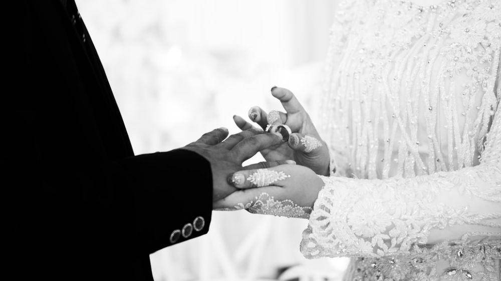 ilustrasi pengantin sedang memakaikan cincin (unsplash.com/Agung Raharja)