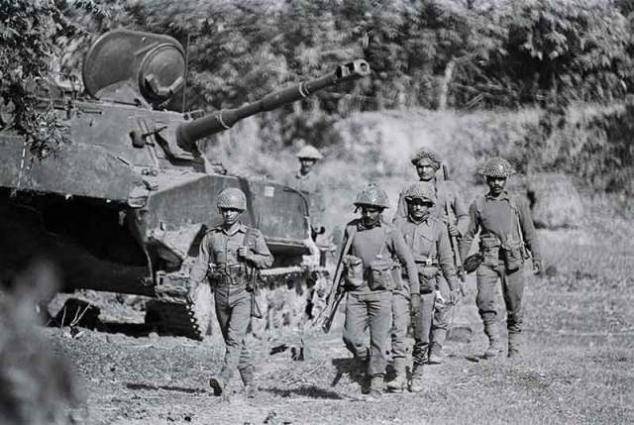 Pada bulan Desember 1971, pasukan Pakistan dan India bentrok di Khulna, di tempat yang sekarang disebut Bangladesh. Dalam foto ini, tentara India berjalan melewati tank India yang hancur. (brookings.edu/CORBIS/Dave Kennerly)