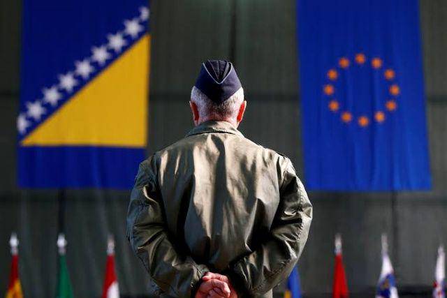 Seorang veteran perang Bosnia-Herzegovina memandangi bendera NATO dan Bosnia-Herzegovina. (nationalinterest.org)